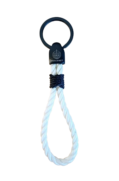 Der Bracenet Schlüsselanhänger II weiße Kordel ist mit einem schwarzen Ring, einem schwarzen Bracenet-Verbinder und einer Schlaufe aus gedrehtem weißem, upgecyceltem Geisternetzseil ausgestattet, das mit schwarzem Faden gesichert ist - perfekt für alle Fans des THW Kiel.