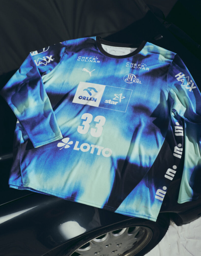 Auf der Motorhaube eines dunklen Autos prangt das THW Kiel 25-26 GK Trikot Home by PUMA in navy mit Sponsorenlogos und der Nummer 33.