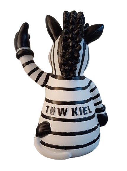 Die Lampe Maskottchen ist eine schwarz-weiß gestreifte Zebrafigur aus Polyresin, die sitzend und winkend mit "THW KIEL" auf dem Rücken dargestellt ist. Es hat eine gelockte schwarze Mähne und ist von hinten dargestellt.