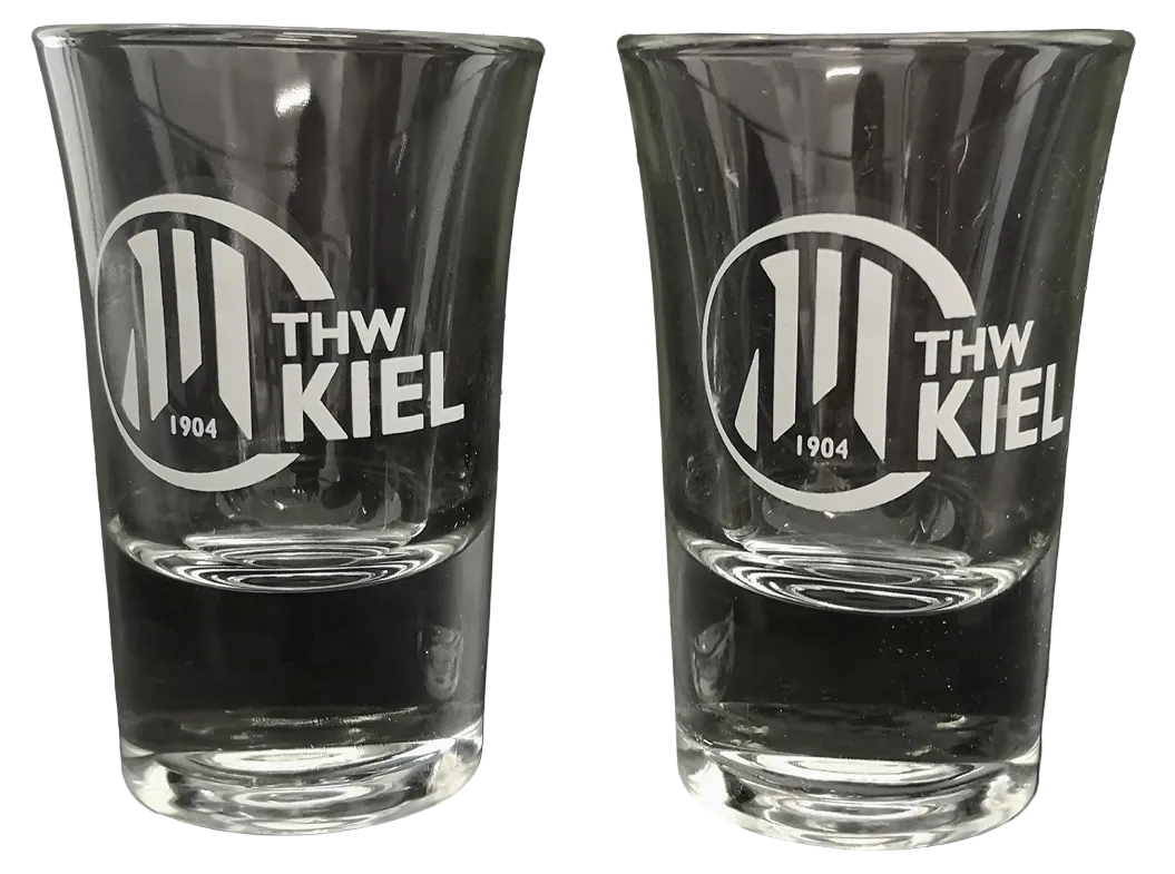 Zwei klare Schnapsgläser 2er mit THW Kiel Logo und 1904 in Weiß nebeneinander vor schwarzem Hintergrund - das perfekte Handball-Fanartikel oder Geschenk für echte Fans.