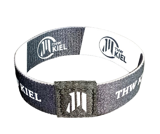 Das Elastische Armband schwarz/weiß ist ein schwarz-weißes RPET-Armband mit dem Schriftzug "THW Kiel", einem kreisförmigen, sich über die gesamte Länge wiederholenden Logo und einem aufgenähten schwarzen Bereich mit weißem abstraktem Muster.