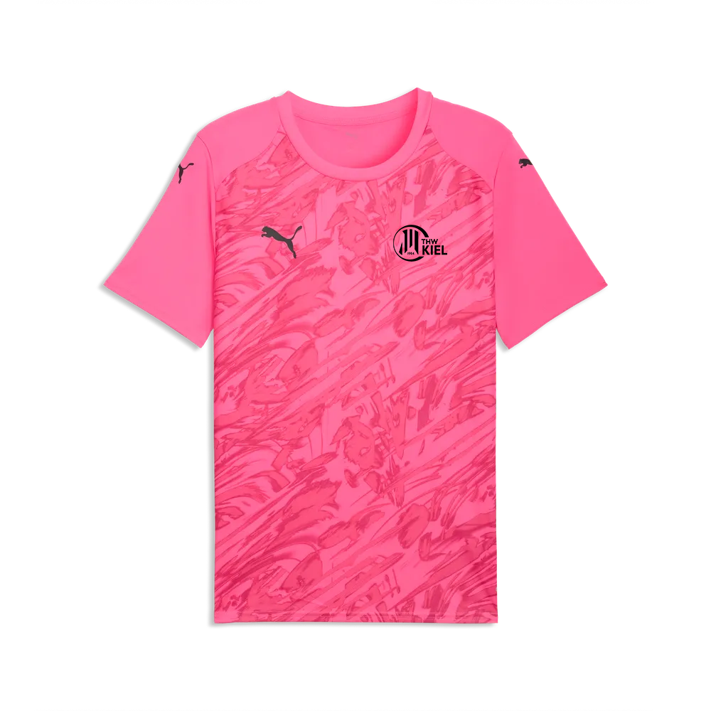 Ein leuchtend pinkfarbenes „teamFINAL Graphic Jersey Jr“-Sportshirt mit kurzen Ärmeln aus recyceltem Polyester, mit einem dezenten abstrakten Design, schwarzen PUMA-Logos auf der Brust und der Schulter sowie einem runden schwarzen Vereinswappen mit der Aufschrift „Kiel“ auf der linken Brustseite.
