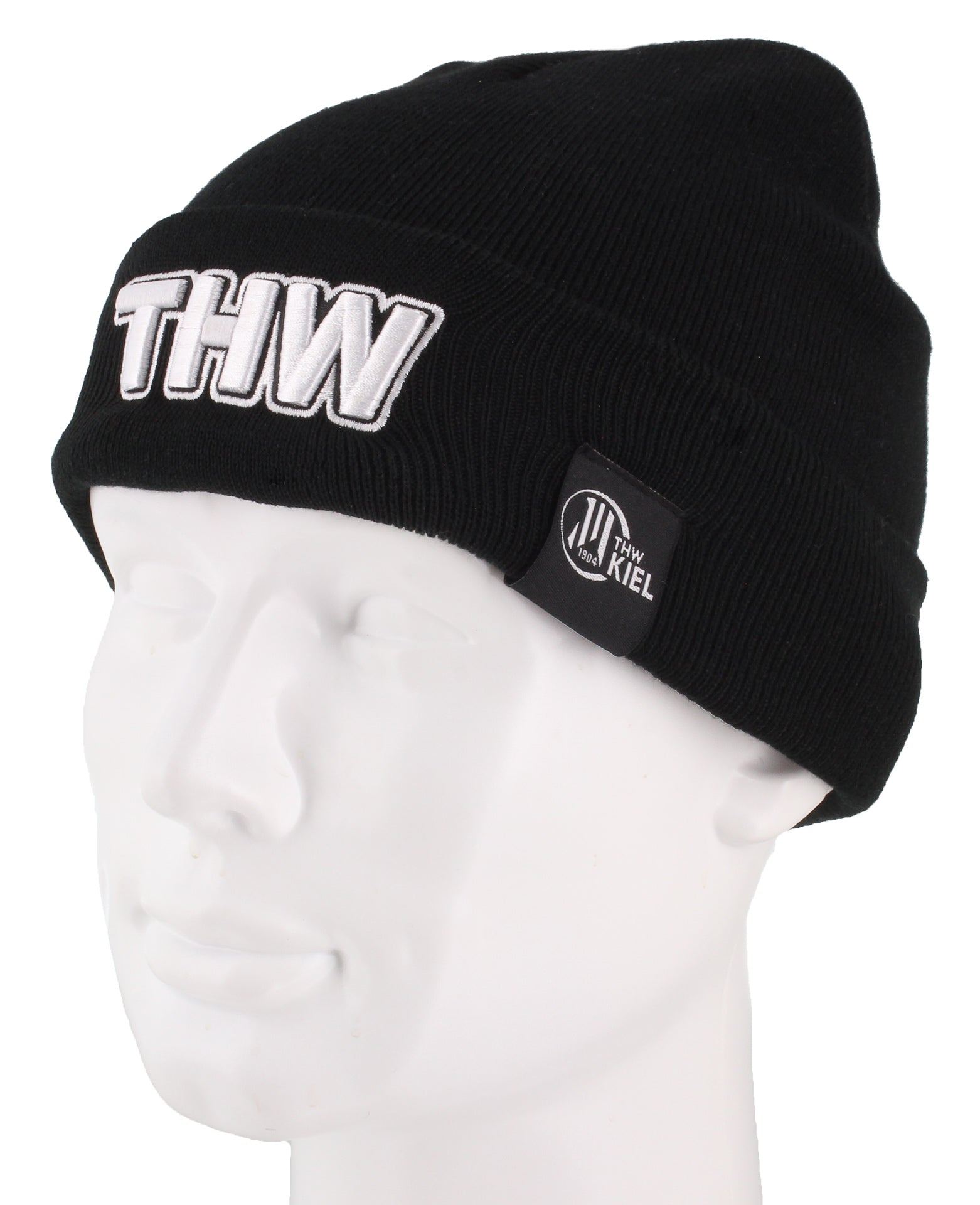 Die Beanie Bronx 3D Stick schwarz hat einen großen weißen "THW"-Schriftzug auf der Vorderseite und einen schwarzen Seitenaufnäher mit "THW KIEL" in weißer Schrift, hier auf einem weißen Puppenkopf.