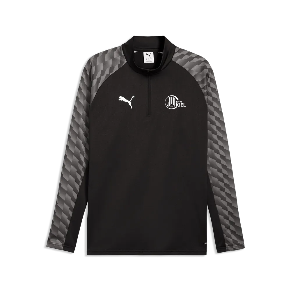 Das teamLIGA26 Training 1/4 Zip Top ist ein schwarzer Sportpullover mit grau gemusterten Ärmeln, einem Viertelreißverschluss, einem weißen PUMA-Logo auf der rechten Brustseite, einem „Kiel“-Wappen auf der linken Brustseite und besteht aus recyceltem Polyester.