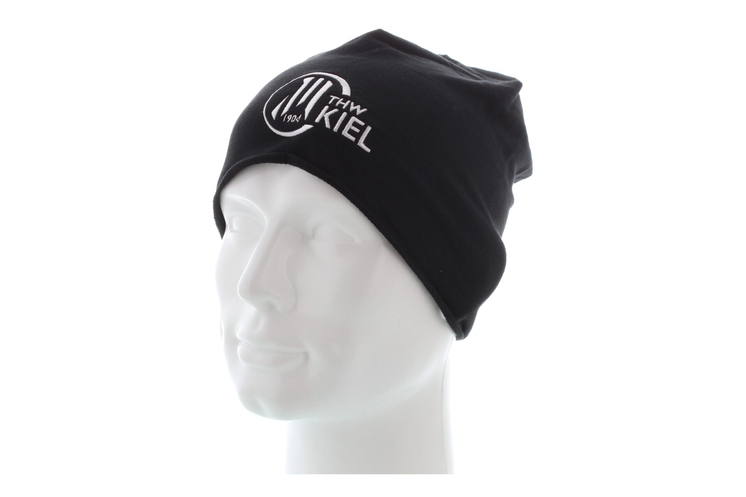 Die Beanie schwarz aus schwarzer Baumwolle mit weißem THW Kiel-Logo auf der Vorderseite ist auf einem weißen Schaufensterkopf vor einem schlichten weißen Hintergrund abgebildet.
